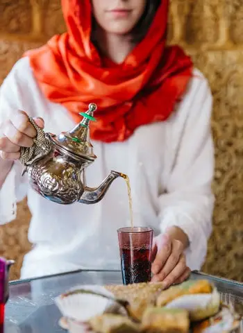 Moteris pila arbatą į stiklinę – jauki akimirka iš arbatos pasaulio su Tea Haven.