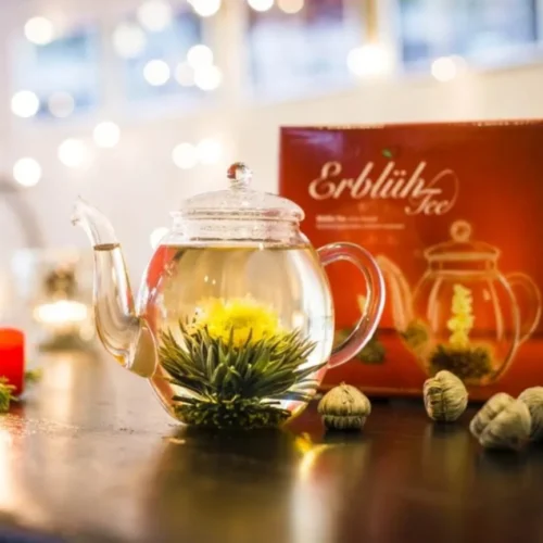 Stiklinis arbatinukas su išsiskleide baltąja arbata ir medetkų žiedu