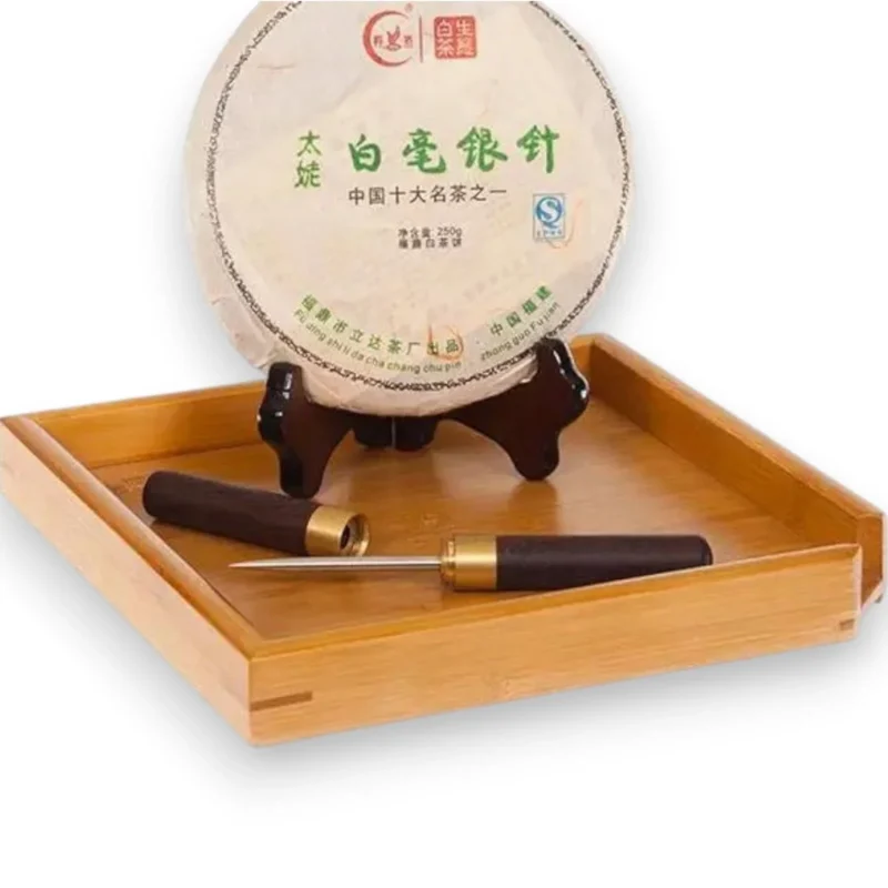 Bambukinis padėklas su presuotos baltosios arbatos disku ir arbatos peiliuku