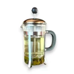 Stiklinis french press kavinukas pilnas žaliosios arbatos baltame fone