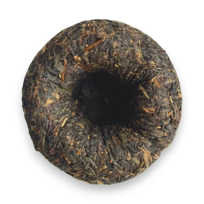 Tamsiai žali brandinti Sheng Pu-erh arbatos lapeliai supresuoti į lizdą