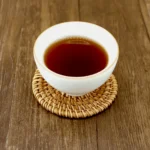Tamsiai raudonas Shou Pu-erh arbatos užpilas baltame porceliano puodelyje