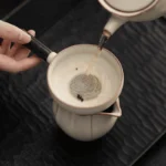 Arbatos pilimas per keraminį sietelį iš arbatinuko į teisingumo indą